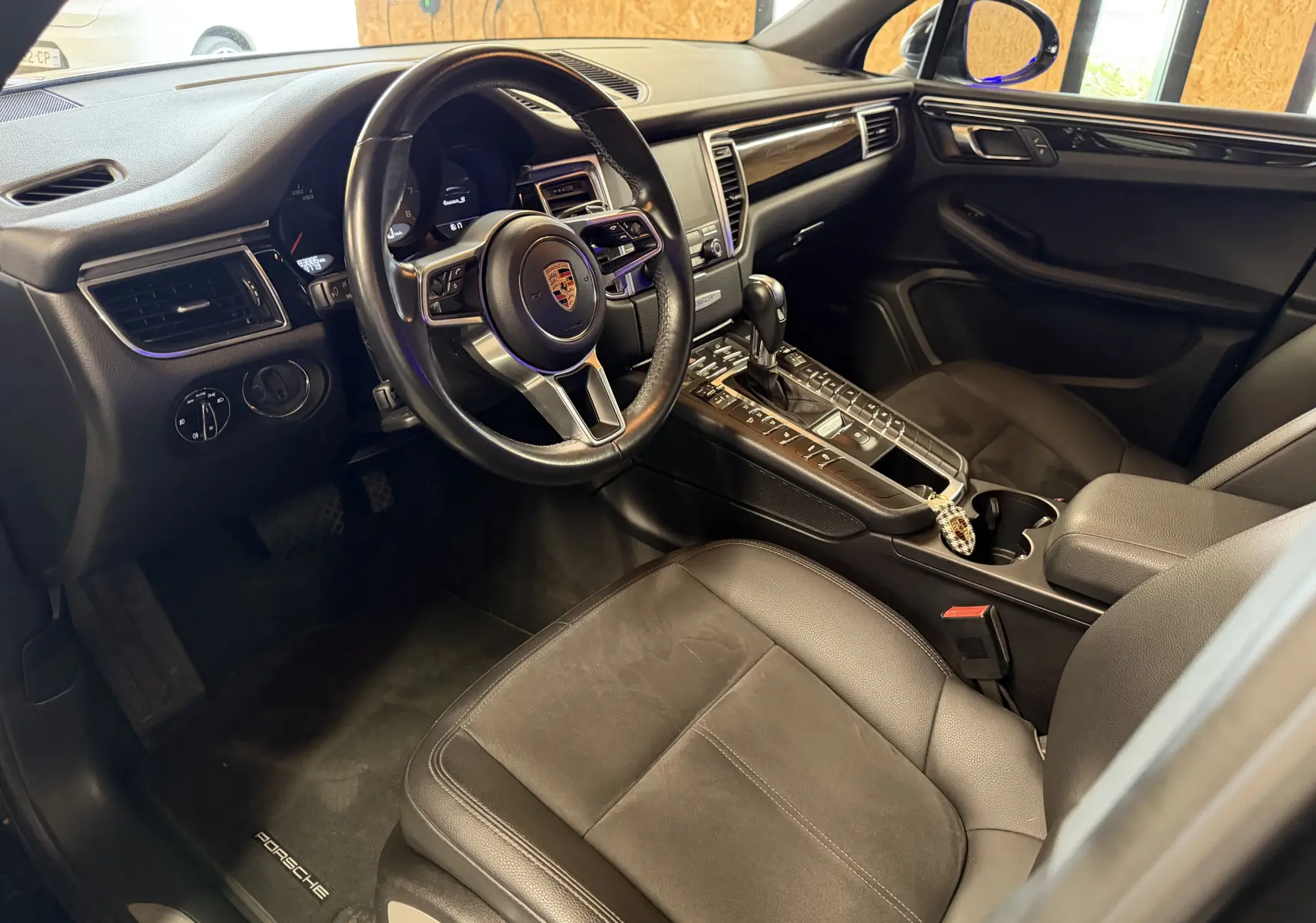 Vue intérieure côté conducteur du Porsche Macan S noir, avec volant cuir multifonctions et console centrale équipée.