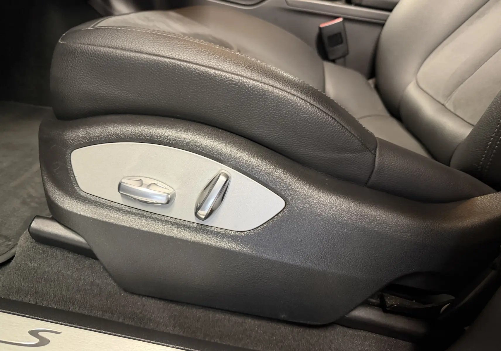 Gros plan sur le réglage électrique du siège avant en cuir noir du Porsche Macan S, avec seuil de porte alu marqué "S".
