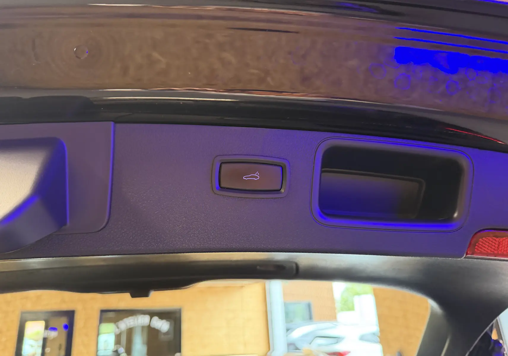 Bouton d'ouverture électrique du hayon sur la partie intérieure du coffre d'un Porsche Macan noir.