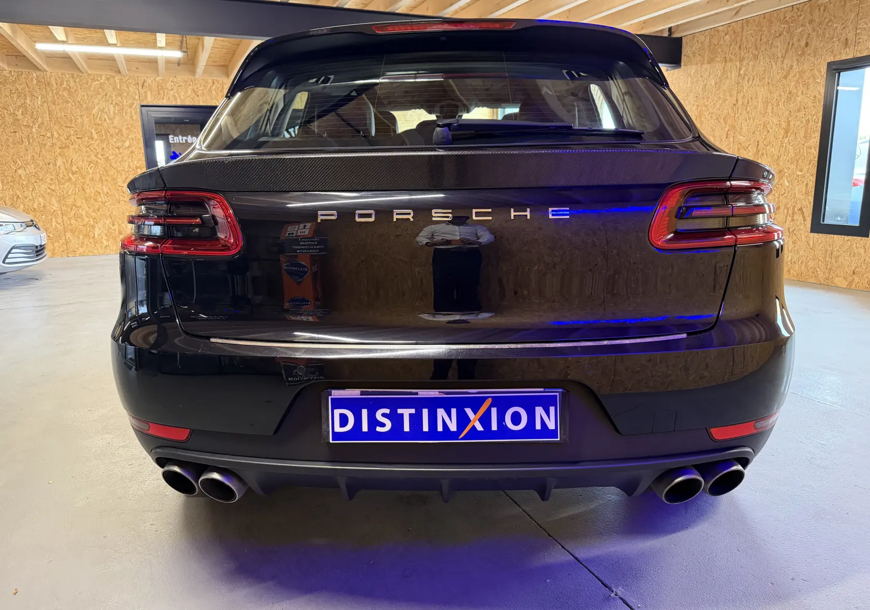 Vue arrière d'un Porsche Macan S noir avec feux LED, double sortie d'échappement sport et logo Porsche lumineux.
