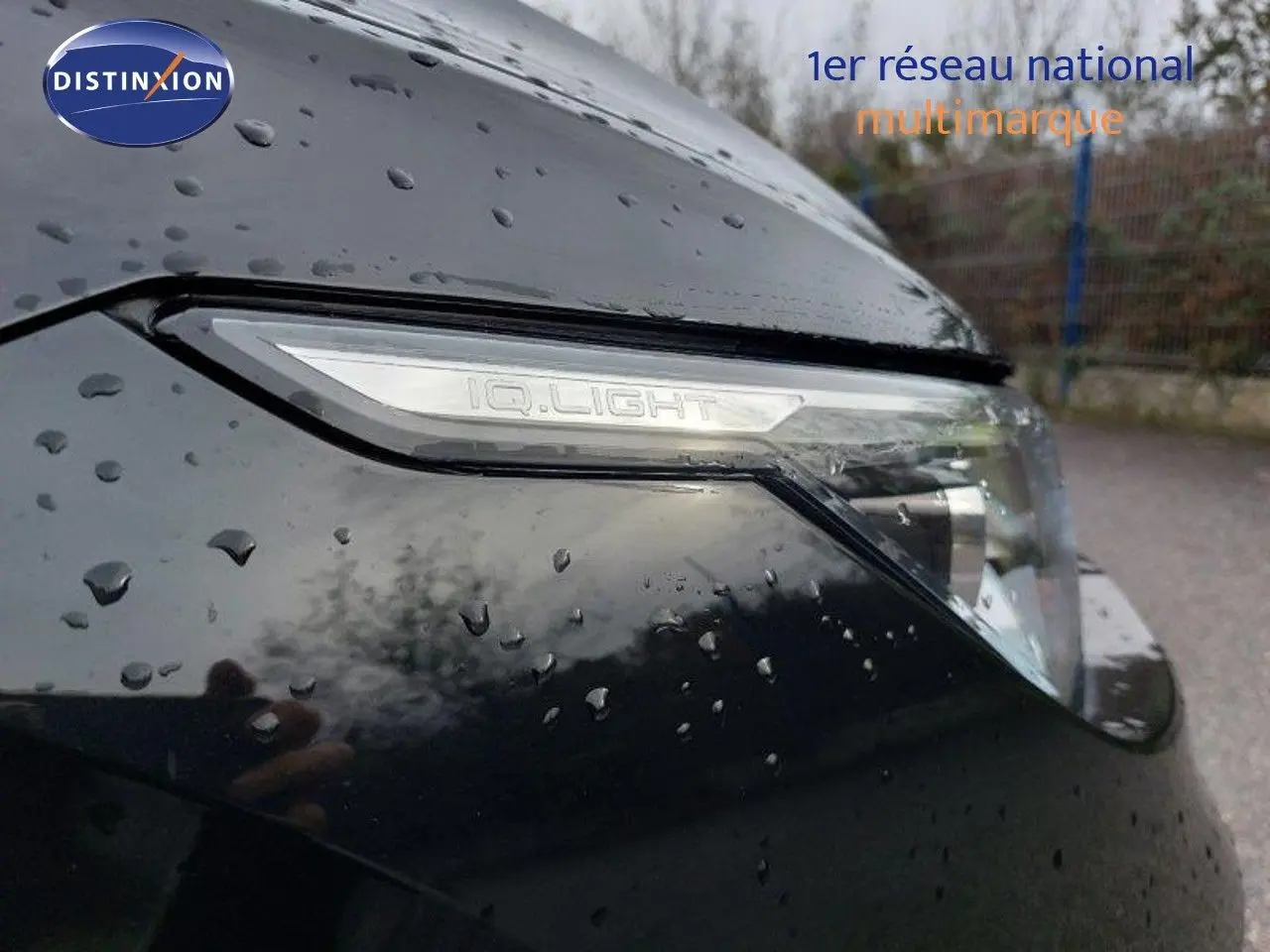 Gros plan sur le phare avant droit noir métal de la Volkswagen Golf 1.5 TSI 150ch 2024 avec pluie visible sur la carrosserie.