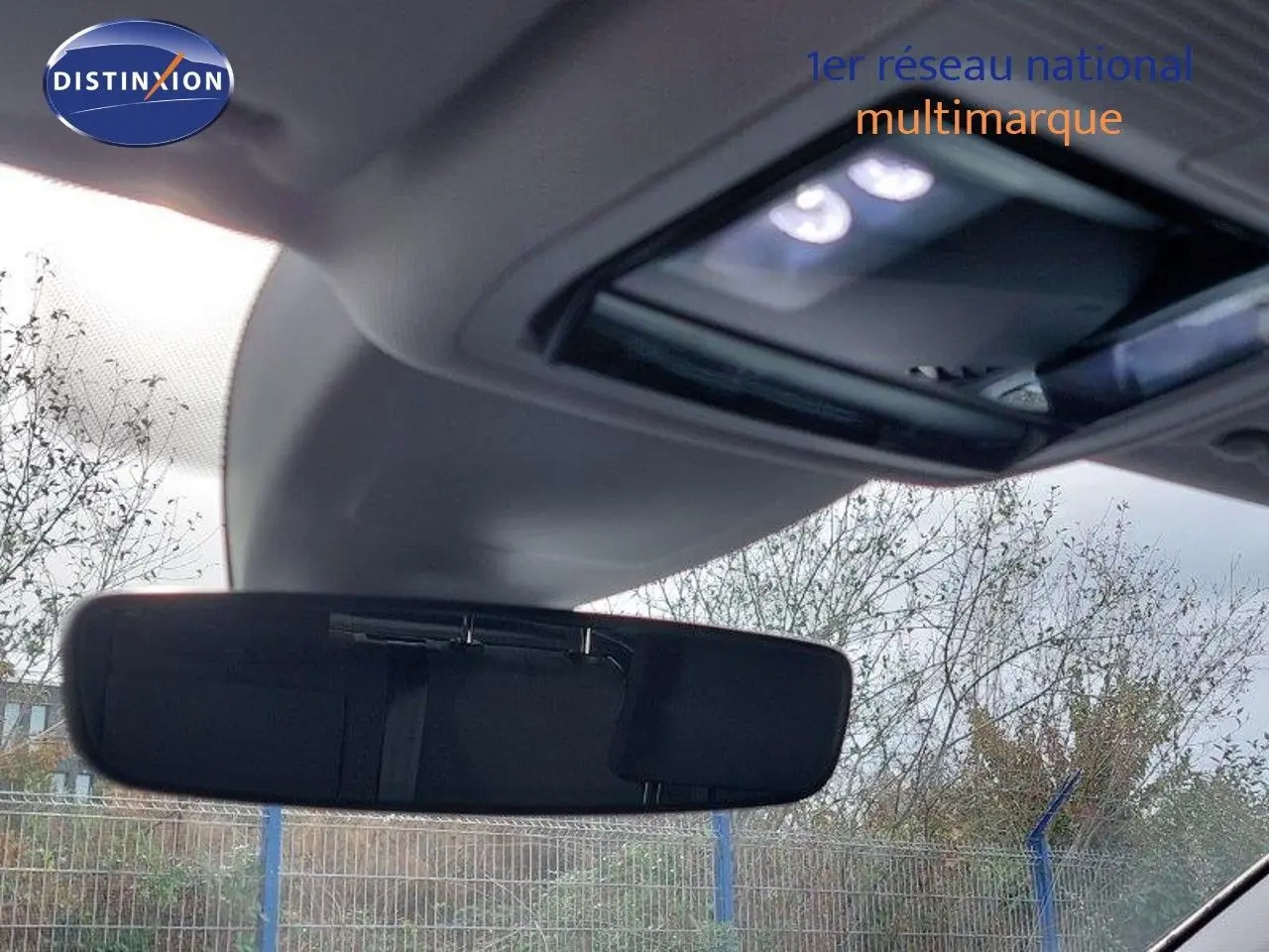 Vue intérieure centrée sur le rétroviseur intérieur d'une Volkswagen Golf noire métal 2024 avec toit ouvrant partiel visible.