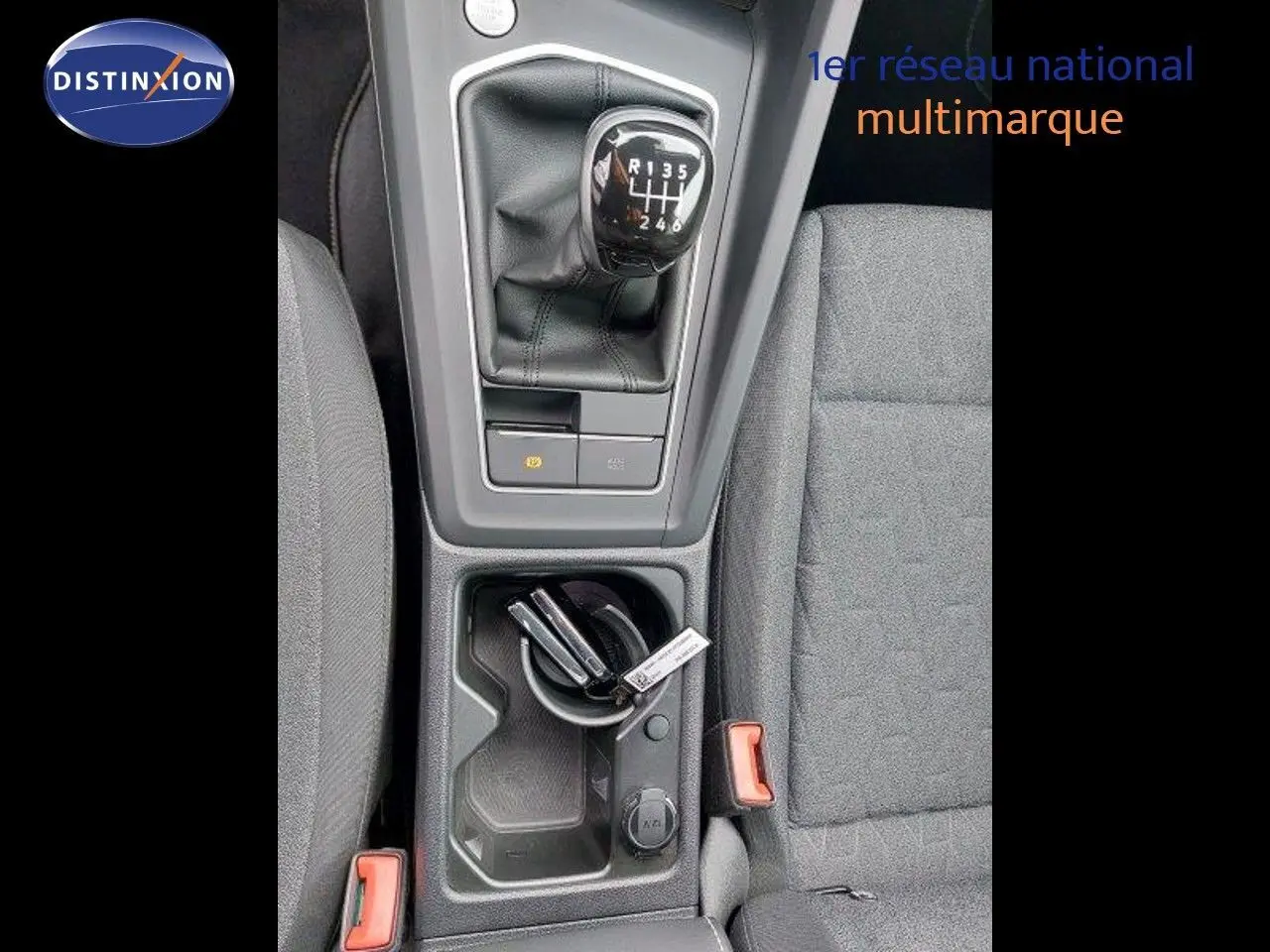 Vue plongeante sur la console centrale de la Volkswagen Golf noire, mettant en valeur le levier de vitesse manuel et les sièges tissu gris.