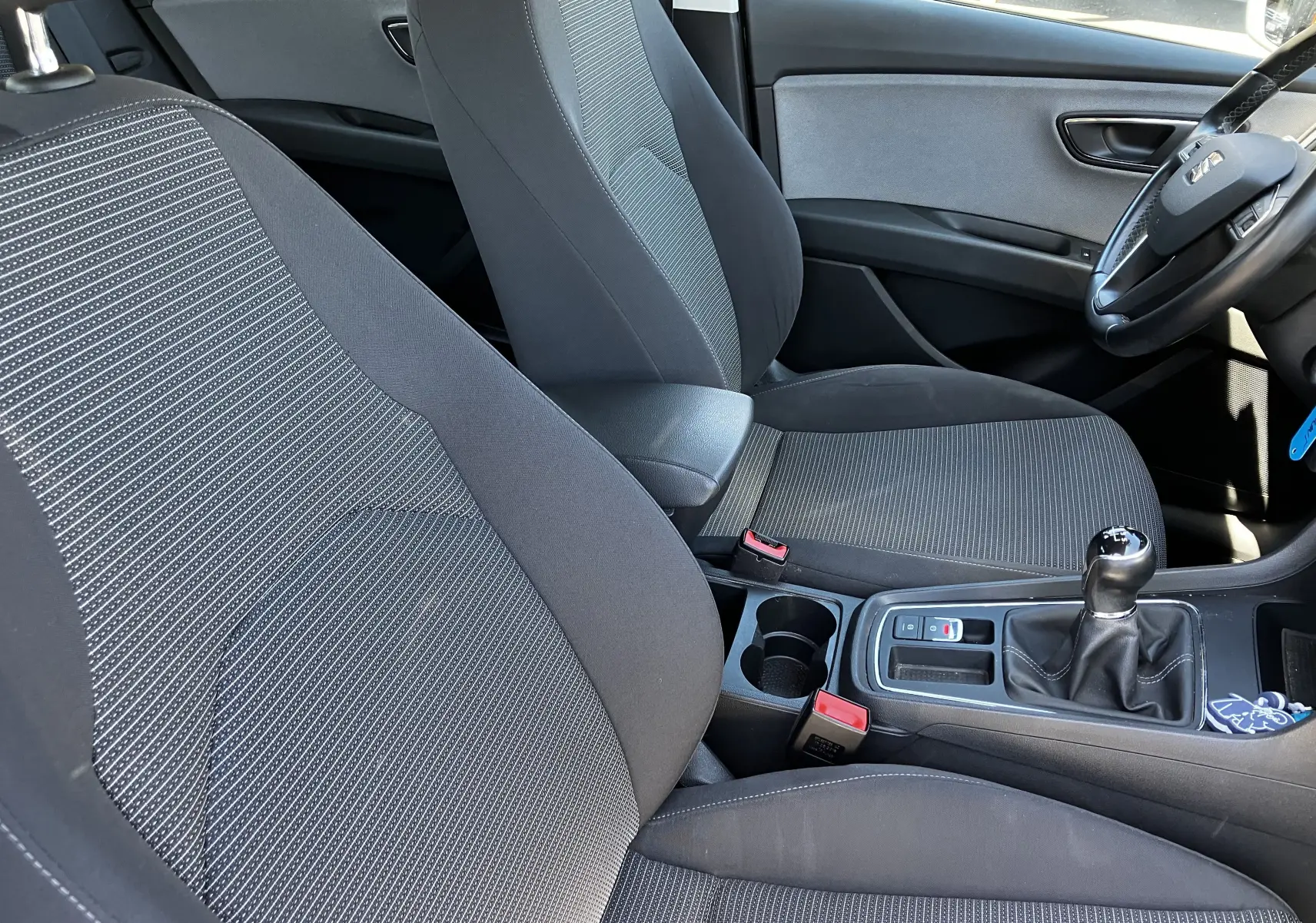 Vue intérieure côté conducteur du SEAT LEON noir 2018, montrant les sièges en tissu noir et la boîte manuelle.