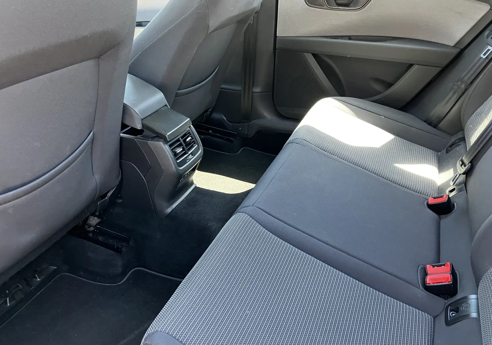 Vue intérieure arrière côté droit du SEAT LEON noir, montrant les sièges arrière en tissu noir et les aérateurs centraux.