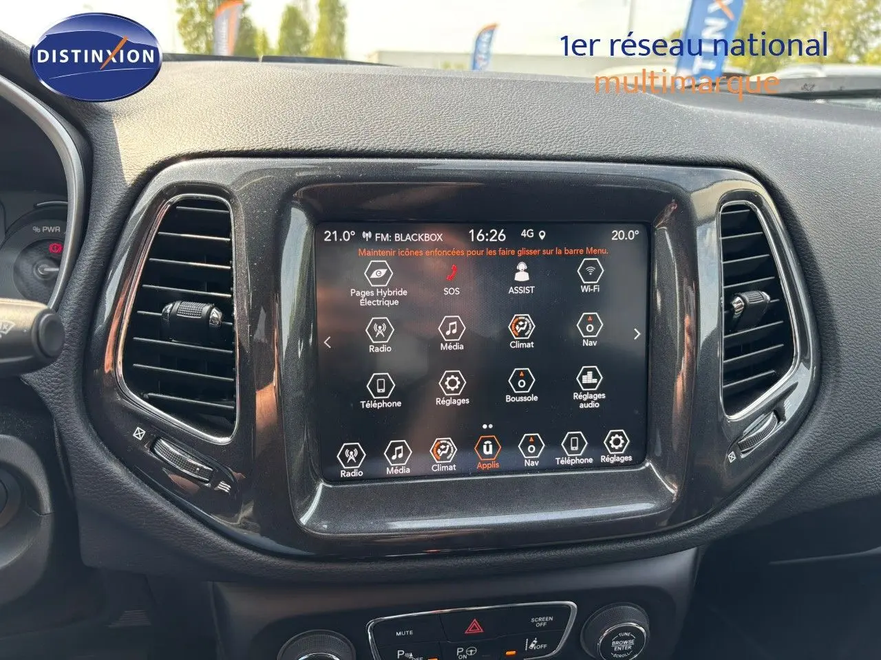 Écran tactile central du tableau de bord du Jeep Compass blanc, affichant les commandes multimédia et climatisation.