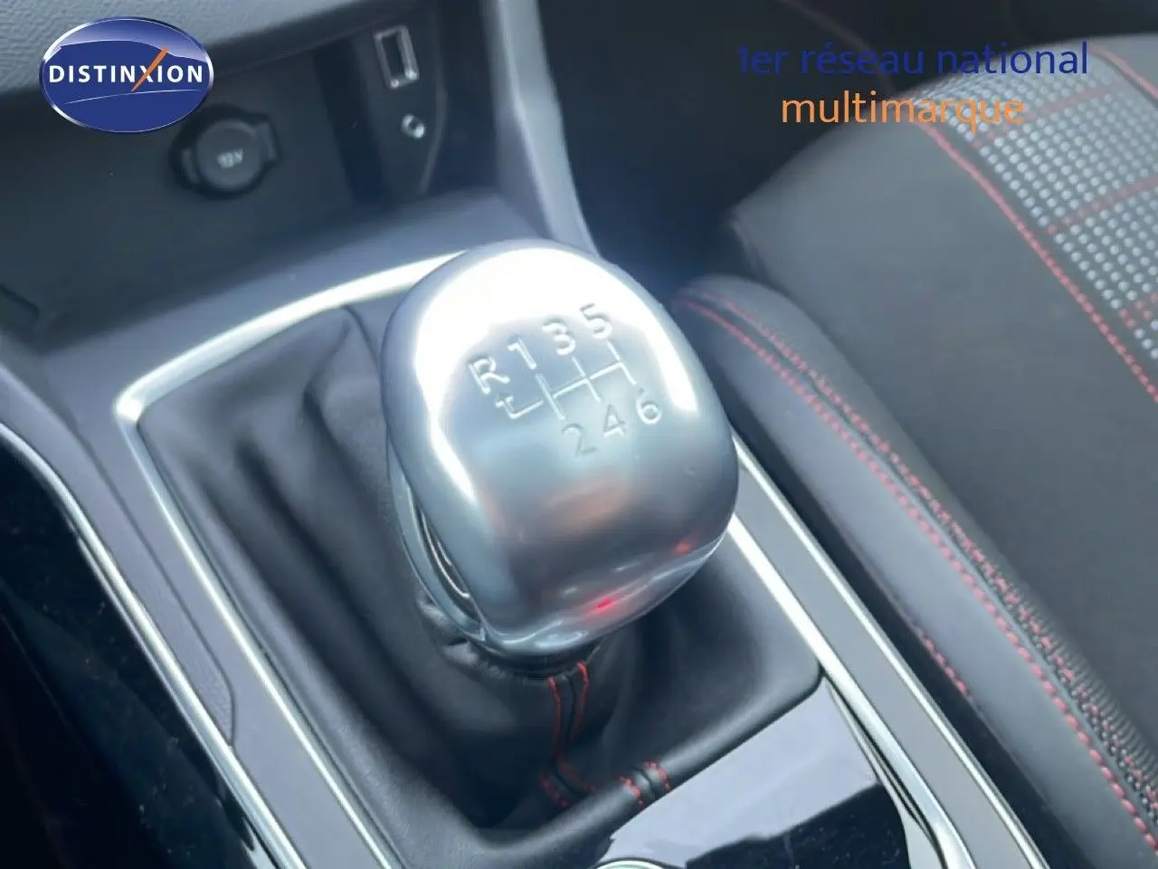 Gros plan sur le levier de vitesse manuel argenté de la Peugeot 308 gris Artense, avec couture rouge visible sur le siège à côté.