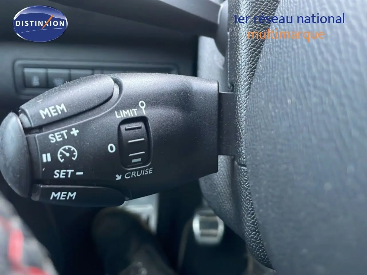 Gros plan sur la commande de régulateur de vitesse noire dans l'habitacle d'une Peugeot 308 gris Artense.