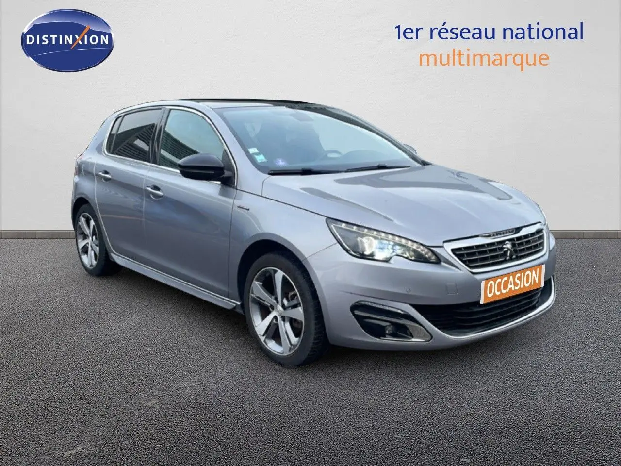 Peugeot 308 gris Artense vue 3/4 avant droit, avec phares LED allumés et jantes alliage distinctives.