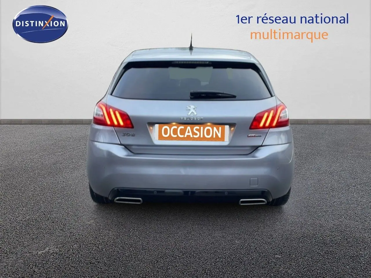 Vue arrière d'une Peugeot 308 gris Artense avec feux LED allumés et double sortie d'échappement chromée.