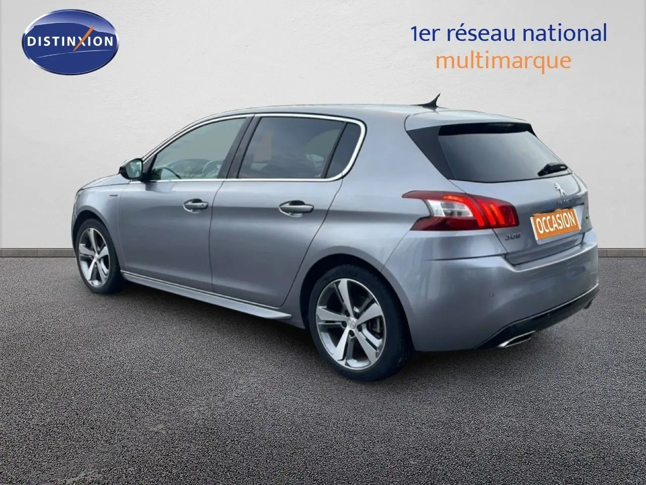 Vue 3/4 arrière droite d'une Peugeot 308 gris Artense avec jantes alliage et vitres teintées.