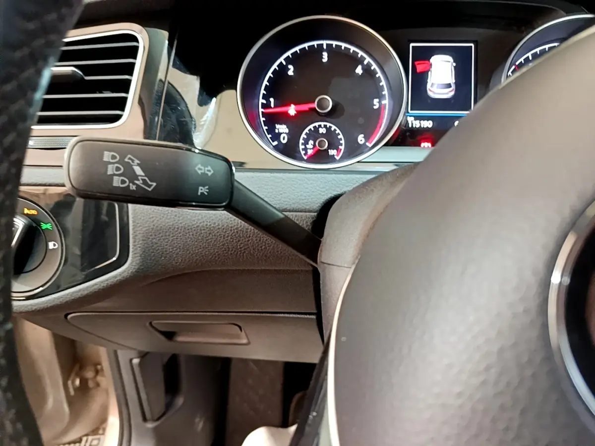 Vue rapprochée du tableau de bord de la Volkswagen Golf gris clair, avec compte-tours et indicateur d'ouverture de porte.