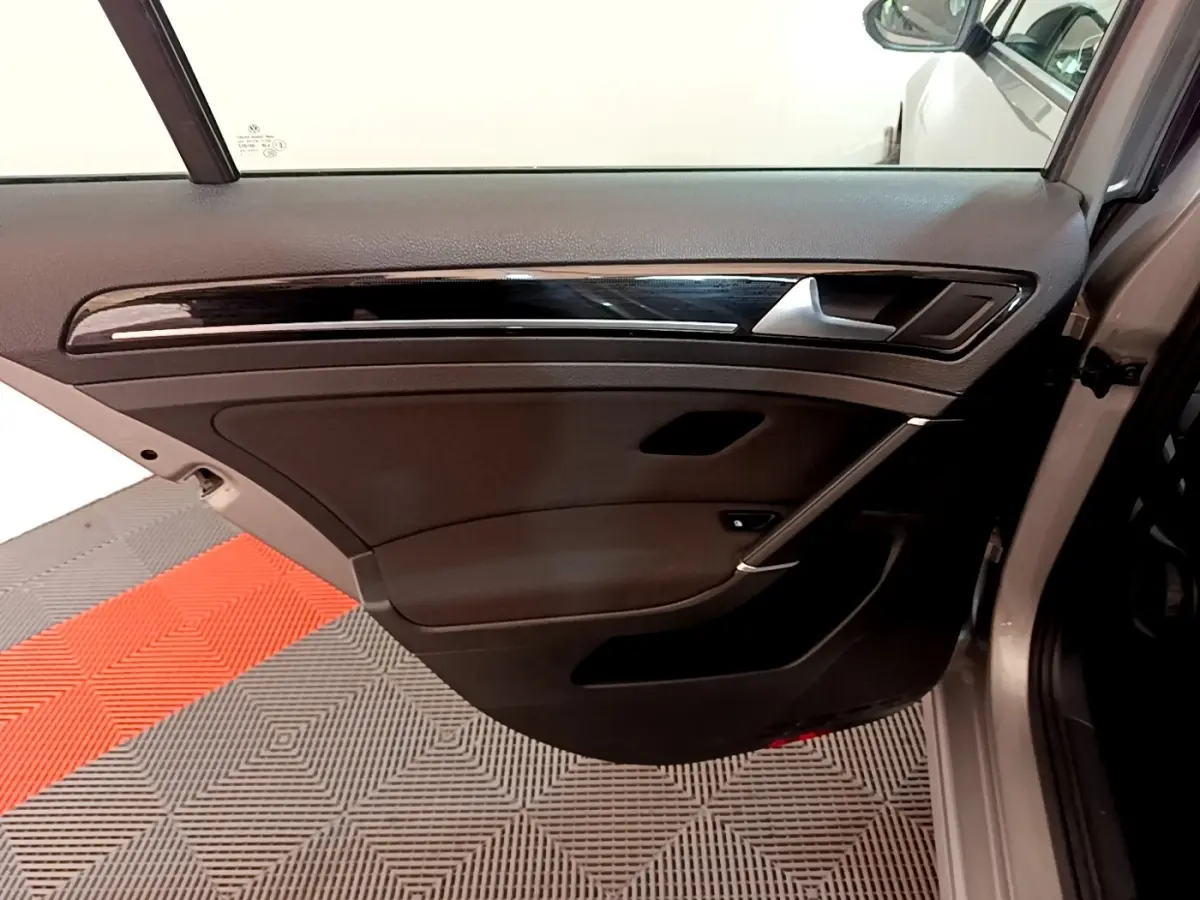 Vue de la porte arrière droite ouverte d'une Volkswagen Golf gris clair, avec garniture noire et insert décoratif brillant.