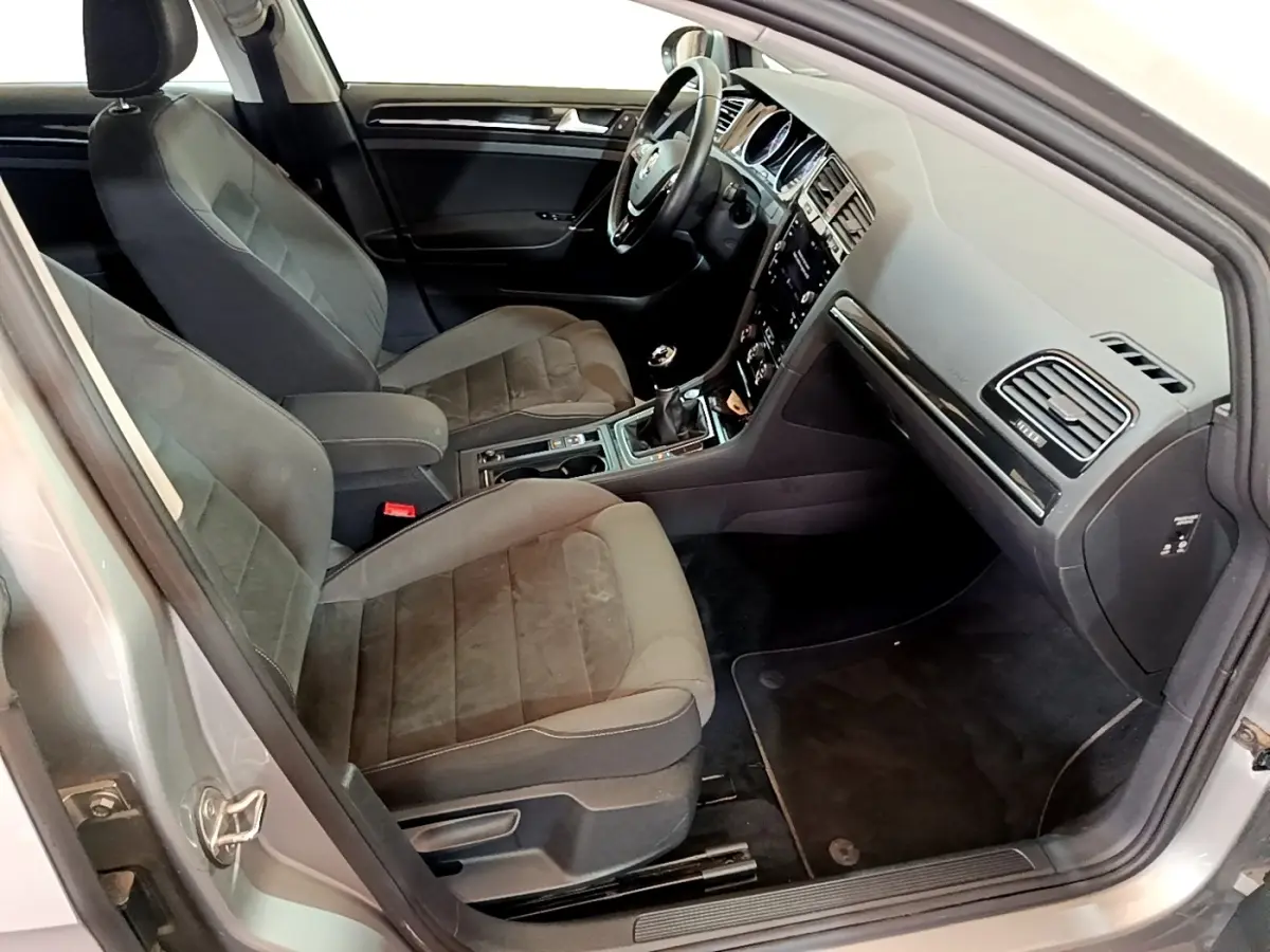 Intérieur avant droit d'une Volkswagen Golf gris clair 2017, sièges tissu et console centrale avec boîte manuelle.