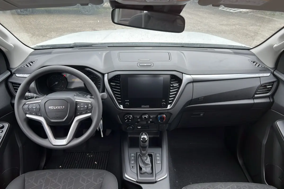 Vue intérieure frontale du tableau de bord et volant multifonctions d’un Isuzu D-MAX blanc, version 2026.