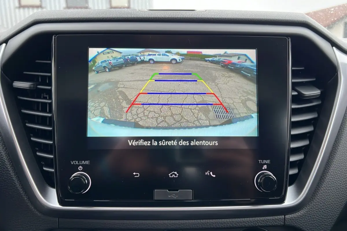 Écran central affichant la caméra de recul du pick-up Isuzu D-MAX blanc, avec lignes de guidage colorées.