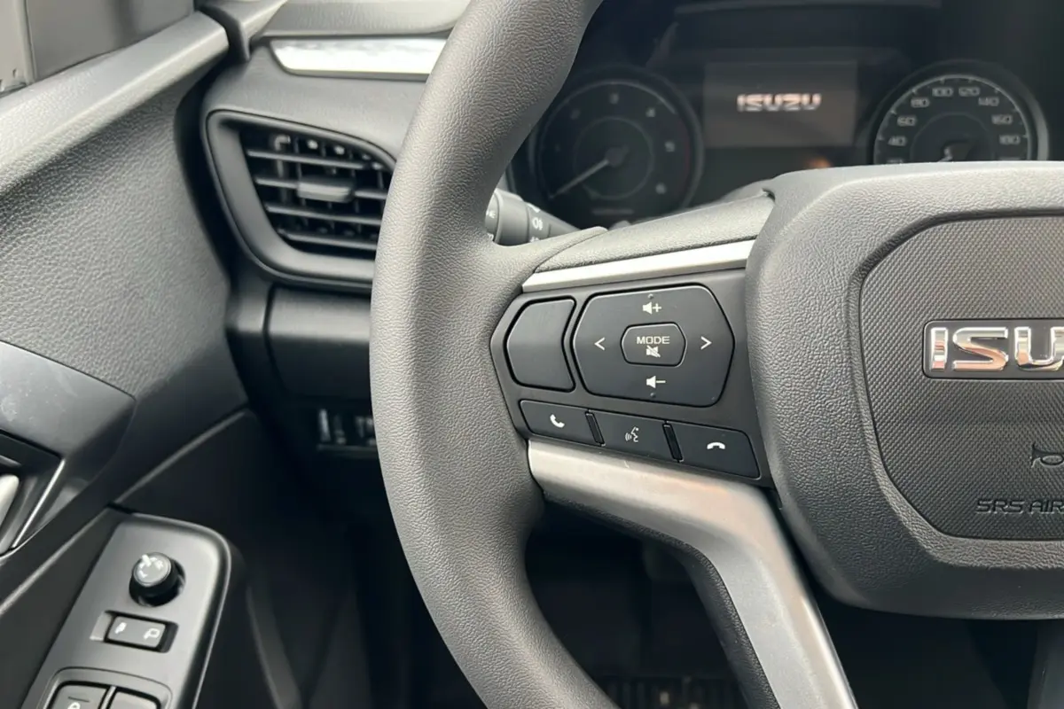 Gros plan sur le volant multifonctions gris foncé de l'Isuzu D-MAX 2026 avec commandes audio et téléphone intégrées.