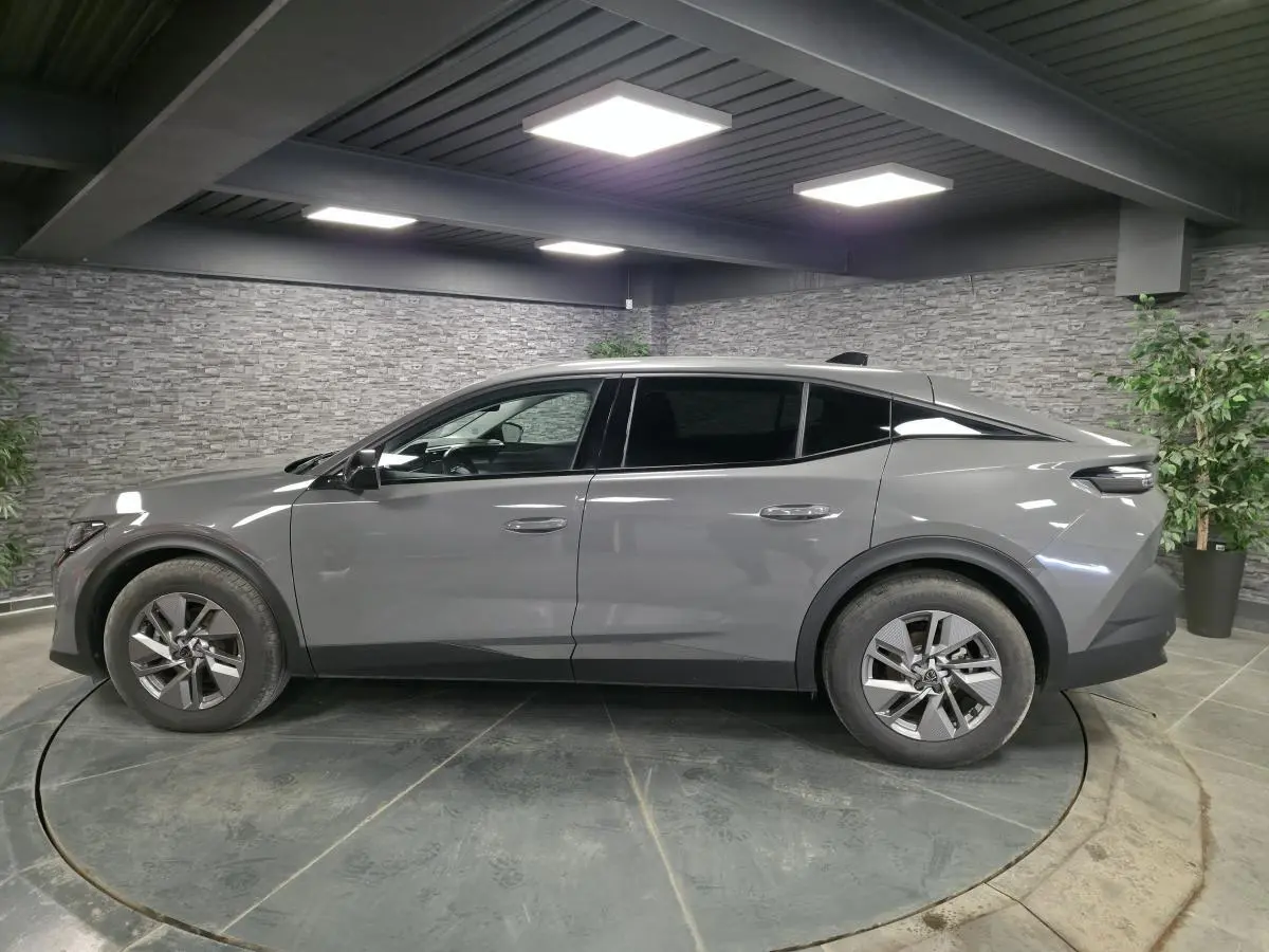 Peugeot 408 gris vue de profil côté gauche dans un showroom avec jantes alliage et vitres teintées.