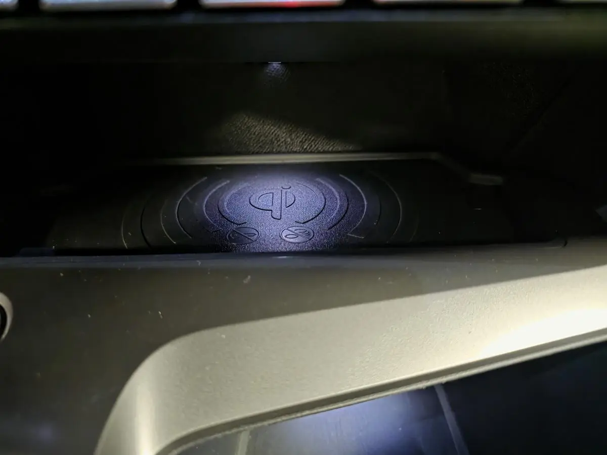 Gros plan sur le chargeur à induction pour smartphone dans l'habitacle de la Peugeot 408 gris, version hybride 2025.