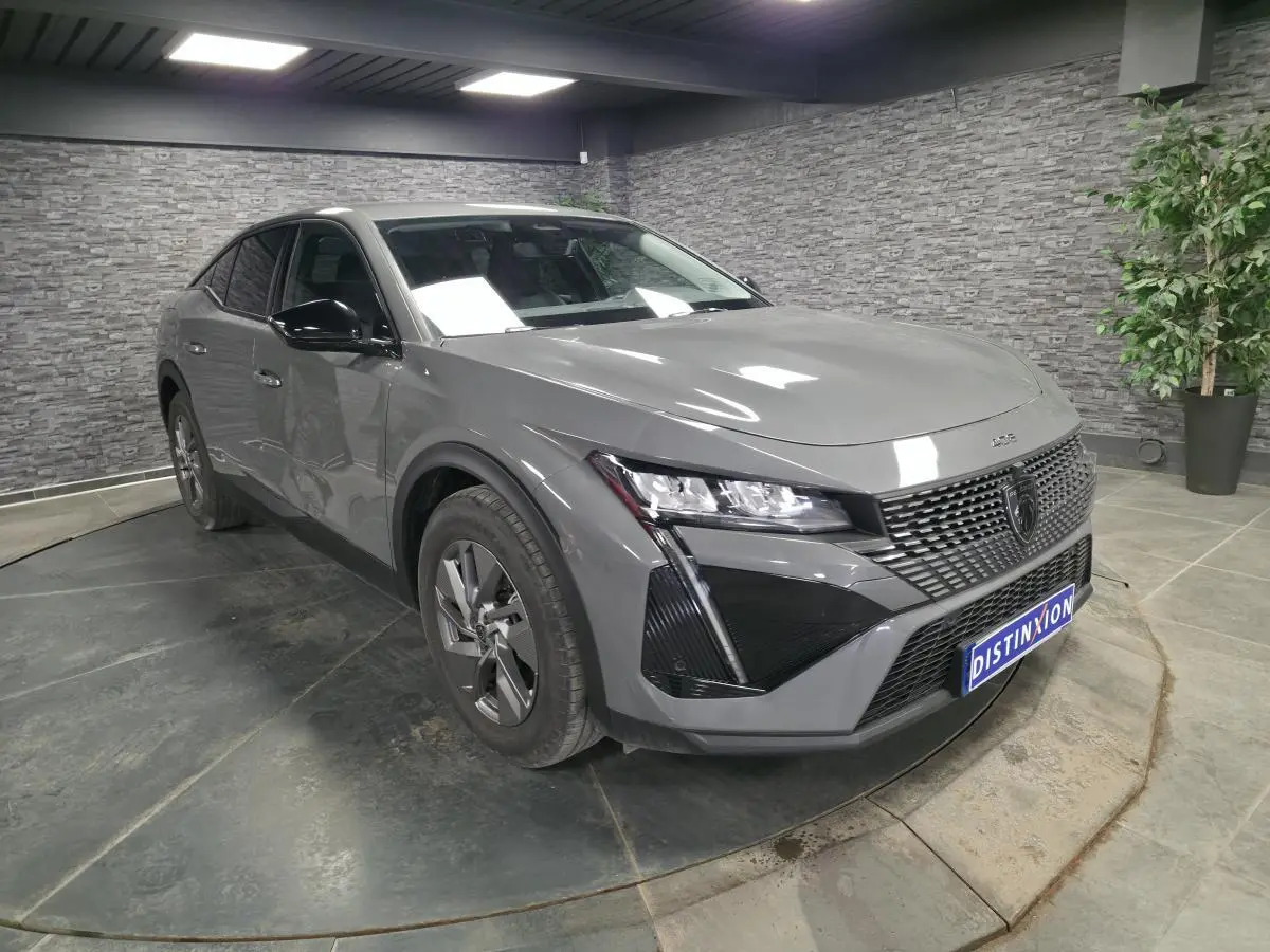 Peugeot 408 gris vue 3/4 avant droit en intérieur avec calandre noire et jantes alliage 17 pouces.