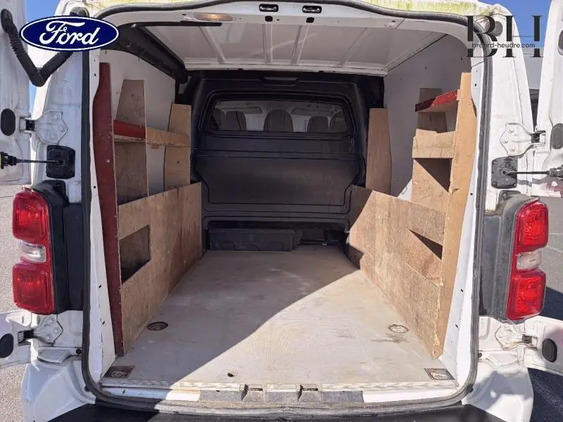 Vue arrière intérieure du fourgon blanc banquise Citroën Jumpy XL avec aménagements en bois sur les côtés.