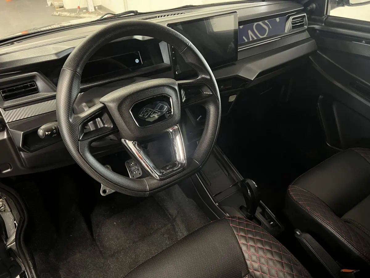 Vue intérieure du tableau de bord et volant noir du Ligier JS50 0.5 REVO D+ Ultimate avec écran tactile central.