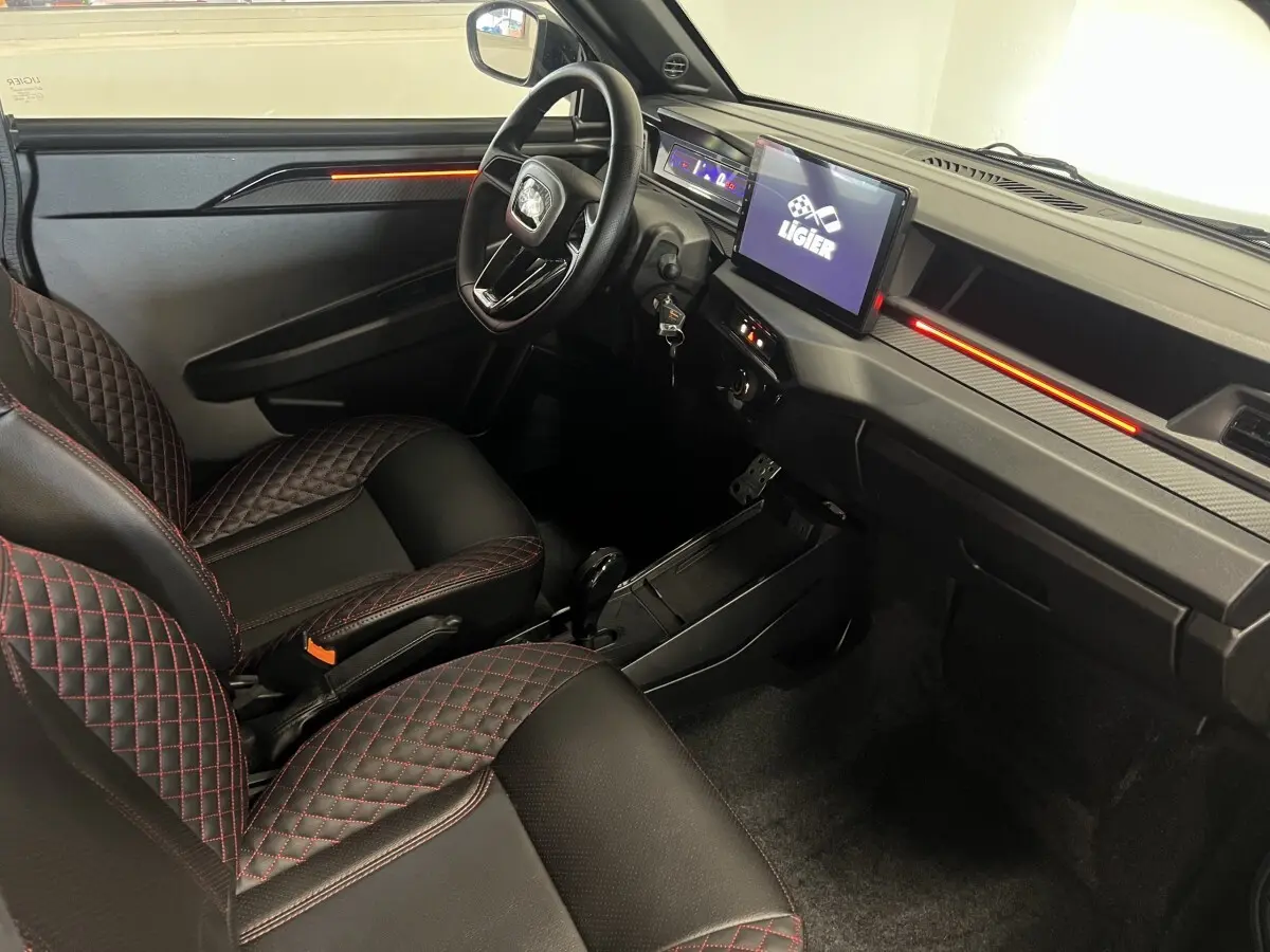 Vue intérieure côté conducteur du tableau de bord et sièges noirs avec surpiqûres rouges du Ligier JS50 2026.