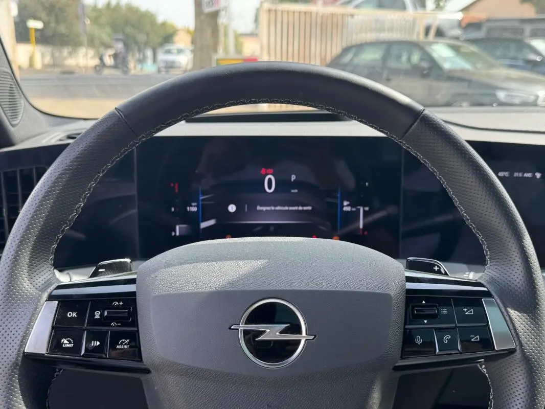 Vue rapprochée du volant cuir gris de l’Opel Astra 2024 avec commandes intégrées et tableau de bord digital.