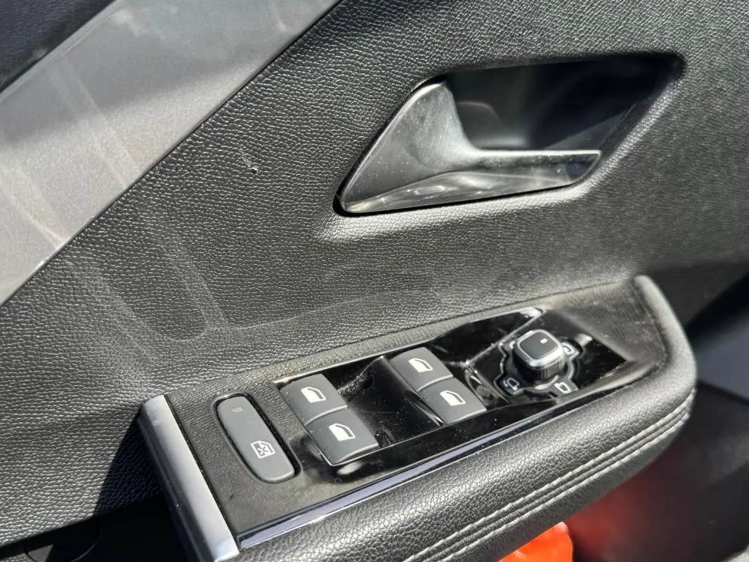 Gros plan sur la commande des vitres électriques et rétroviseurs côté conducteur d’une Opel Astra gris 2024.