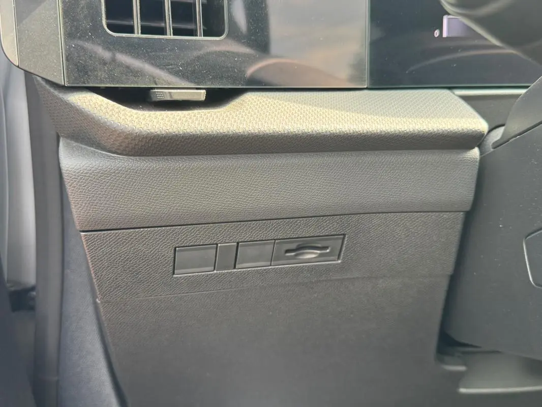 Détail intérieur montrant le bouton d'ouverture du capot sur la planche de bord côté conducteur de l’Opel Astra gris 2024.