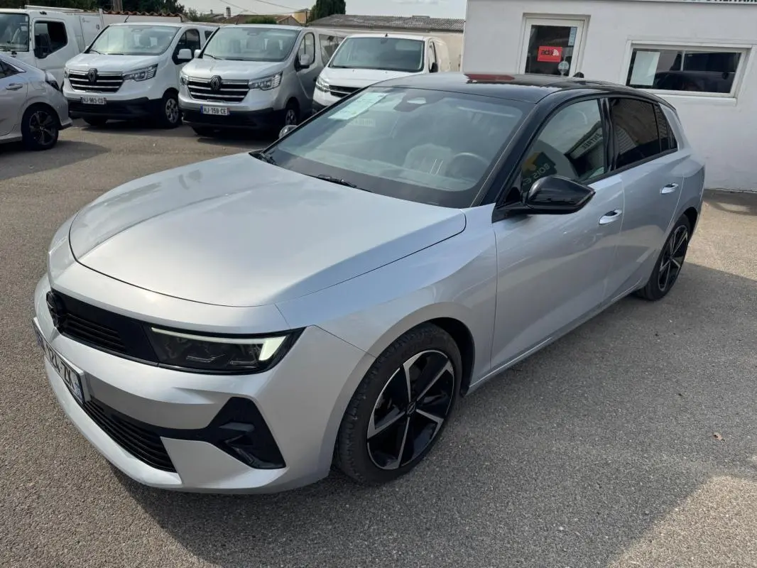 Opel Astra gris 3/4 avant droit avec toit noir, jantes alliage 17 pouces et vitres surteintées.