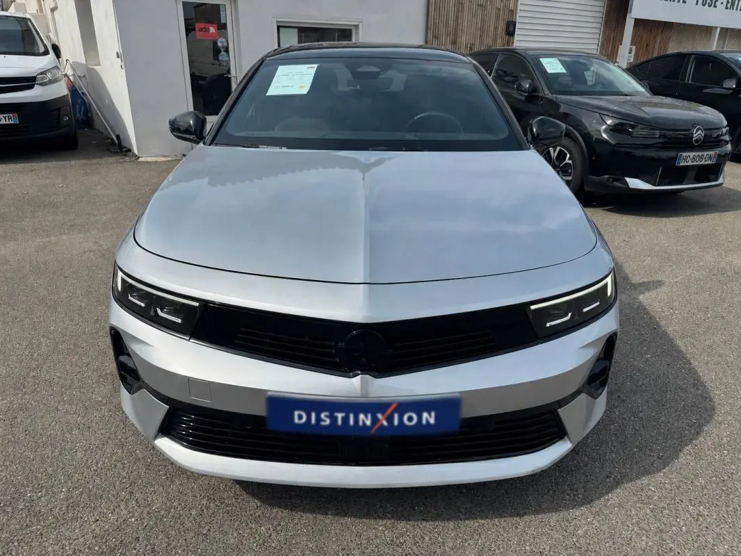 Vue avant d'une Opel Astra gris clair 2024 avec calandre noire et phares LED fins, stationnée en extérieur.