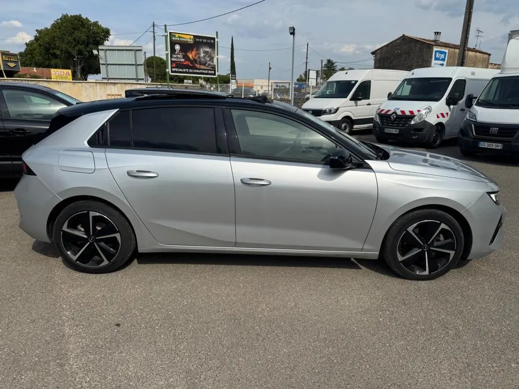 Opel Astra 2024 gris en profil côté gauche, avec jantes alliage noires et vitres surteintées.