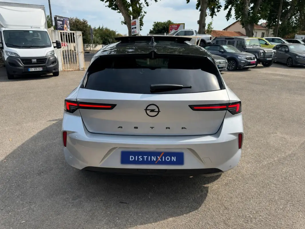 Vue arrière d'une Opel Astra gris clair 2024 avec feux LED horizontaux et vitres surteintées.