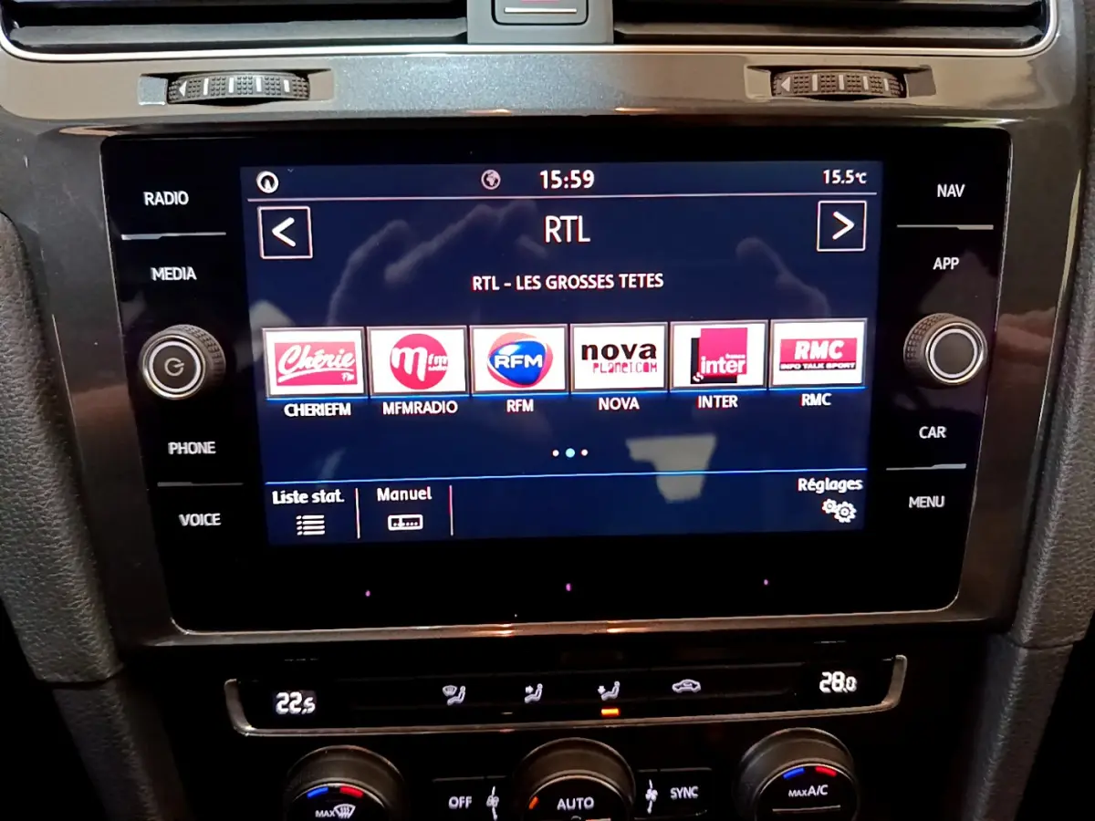 Écran tactile central de la Volkswagen Golf noire 2018 affichant les stations radio avec commandes climatisation en dessous.