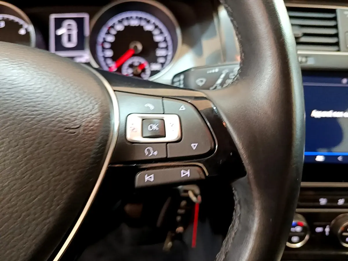 Gros plan sur le volant cuir noir de la Volkswagen Golf 2018, avec commandes multifonctions et tableau de bord en arrière-plan.