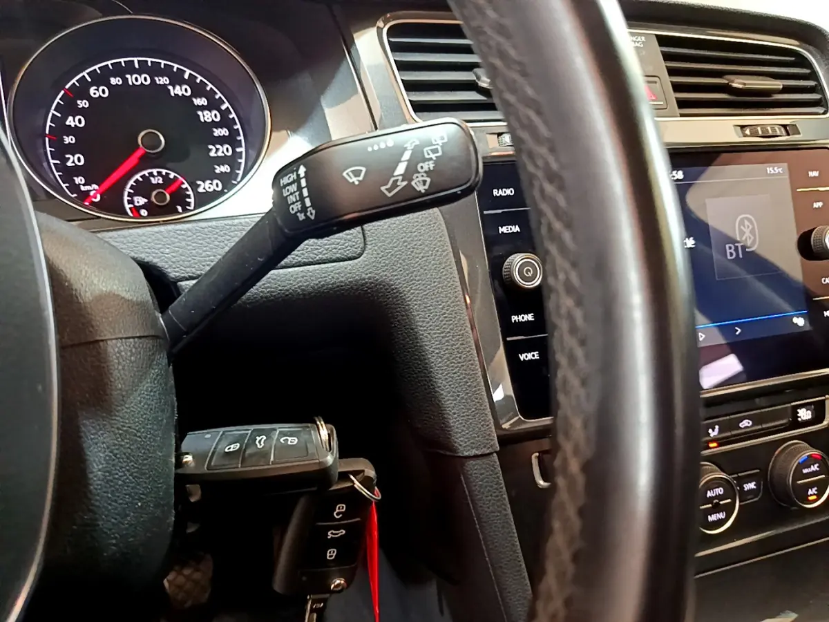 Vue rapprochée du tableau de bord et volant cuir d'une Volkswagen Golf noire, avec écran tactile et commandes au volant visibles.