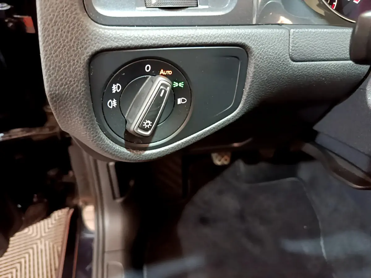 Gros plan sur le bouton de commande des phares dans l'habitacle noir de la Volkswagen Golf 1.6 TDI 2018 côté gauche.