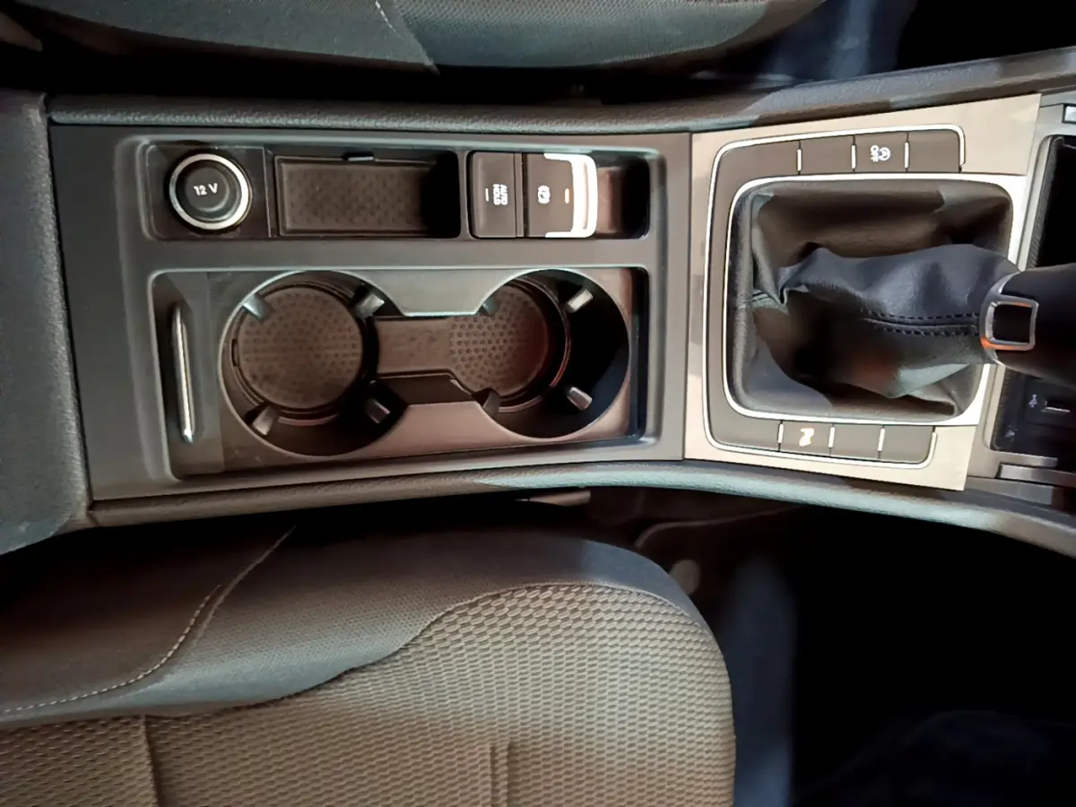 Vue rapprochée de la console centrale noire de la Volkswagen Golf 1.6 TDI 2018 avec levier de vitesse manuel et porte-gobelets.