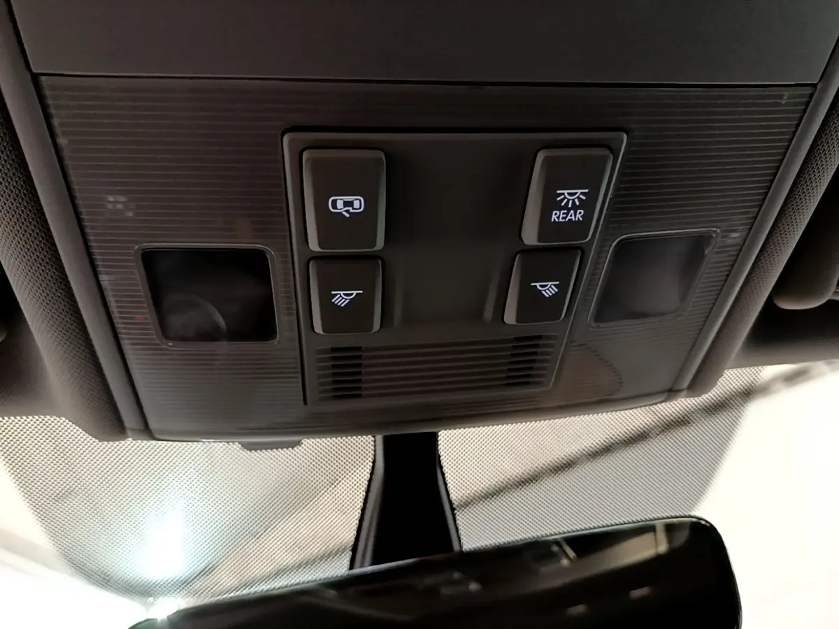Vue en contre-plongée du panneau de commandes d'éclairage intérieur noir de la Volkswagen Golf 2018, avec quatre boutons lumineux.