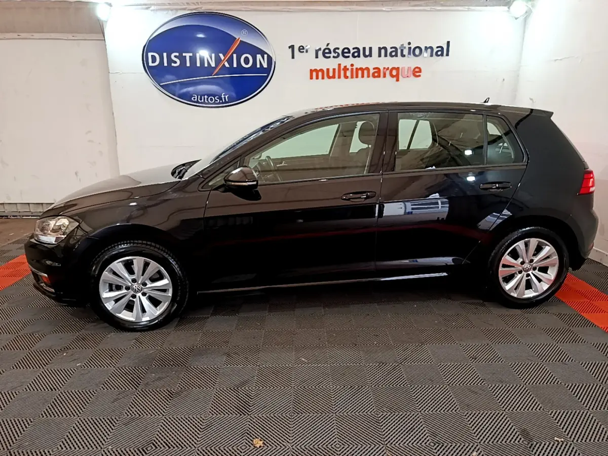 Profil droit d'une Volkswagen Golf noire 2018 garée en intérieur avec jantes alliage visibles et logo Distinxion en arrière-plan.