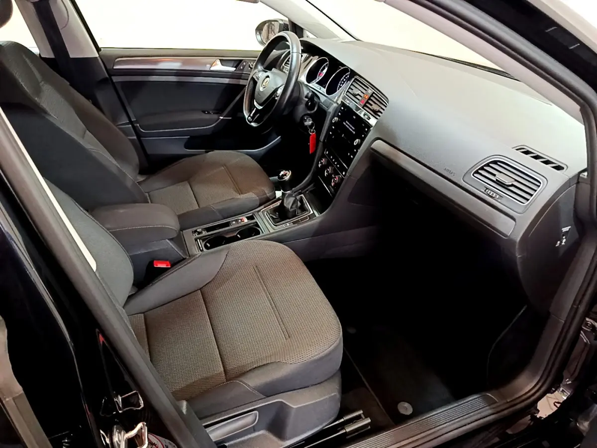 Intérieur de la Volkswagen Golf noir 2018, vue côté conducteur, sièges tissu gris et tableau de bord moderne.