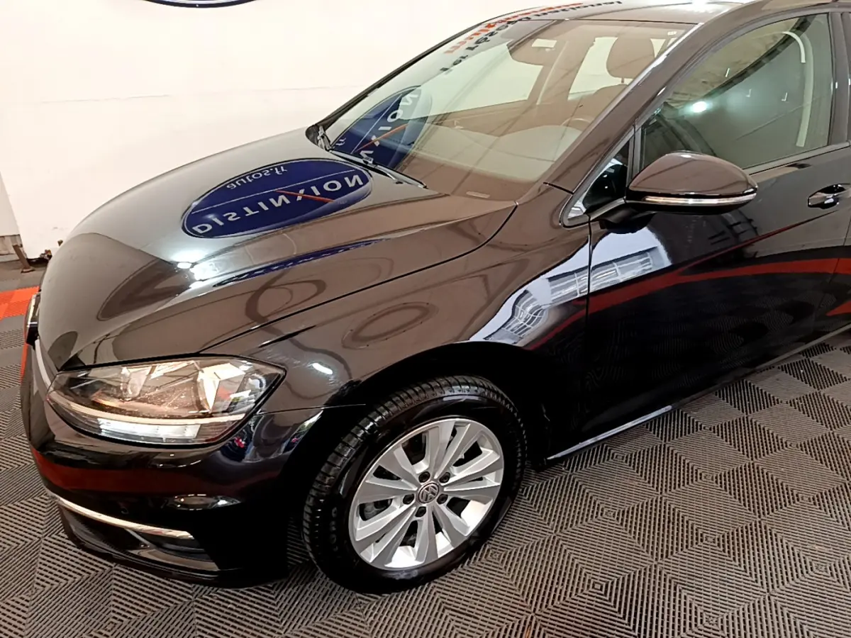 Vue 3/4 avant droit d'une Volkswagen Golf noire 2018 avec phares halogènes et jantes alliage argentées.