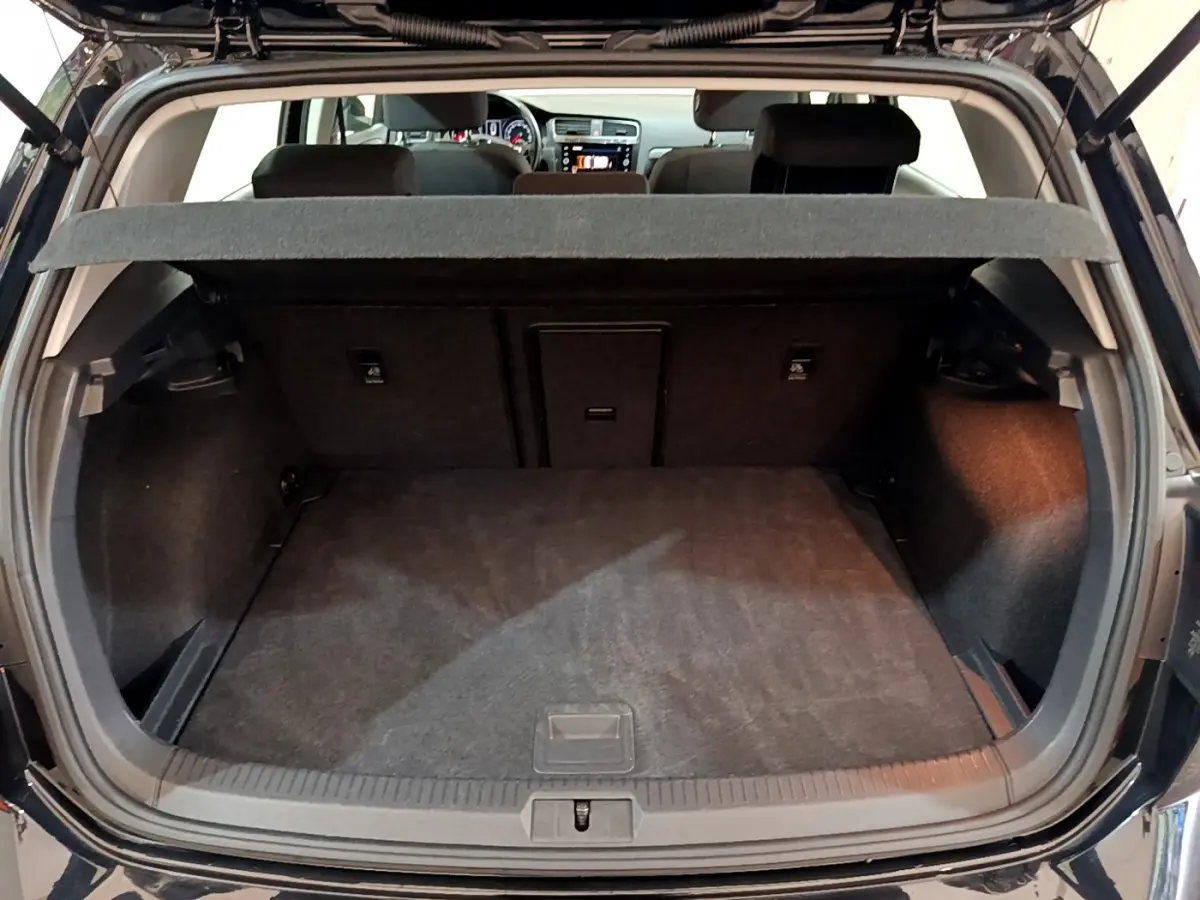Coffre ouvert d'une Volkswagen Golf noire 2018, vue arrière montrant l'espace de chargement et la tablette cache-bagages.