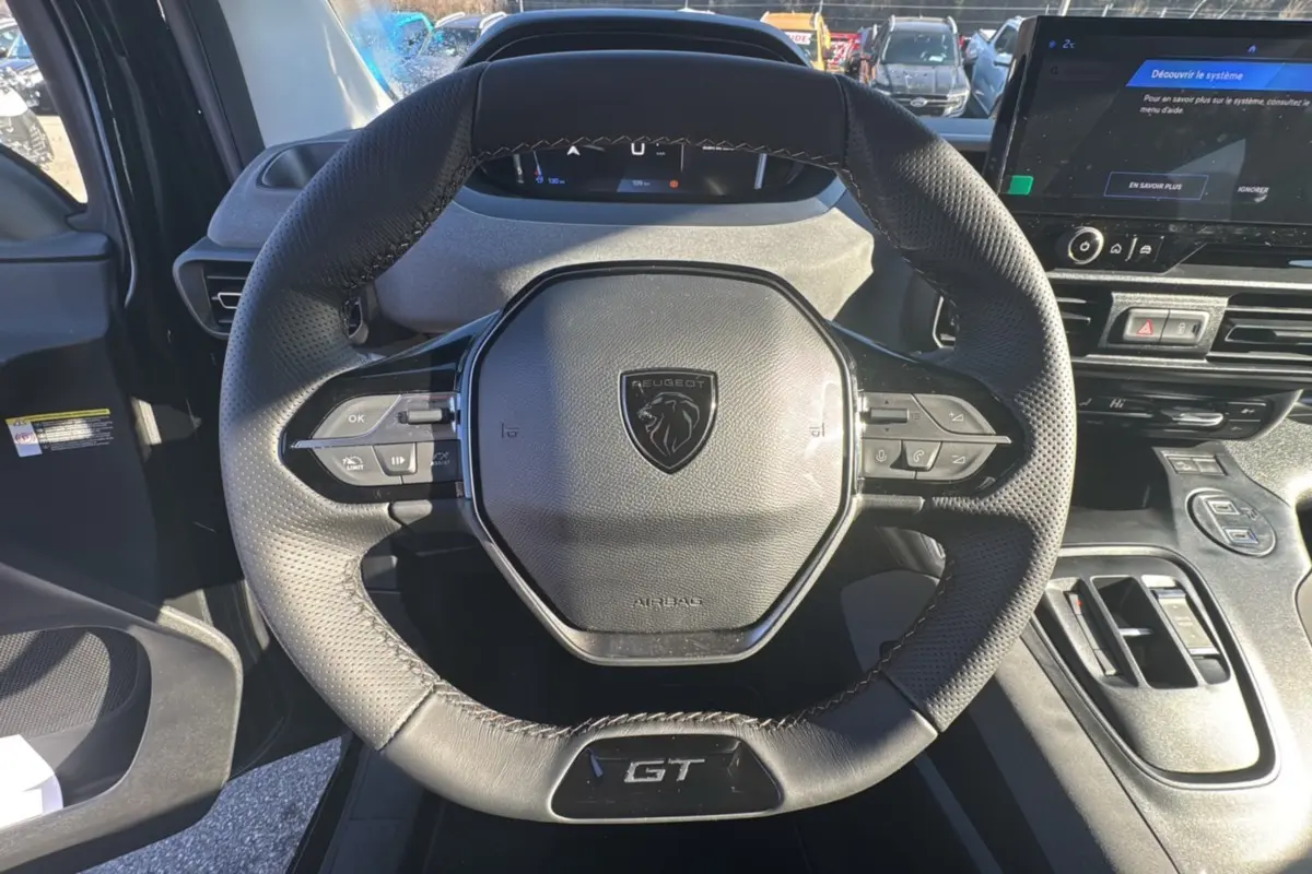 Volant cuir multifonctions noir avec logo Peugeot et badge GT, tableau de bord et écran tactile du Peugeot Rifter 2025.