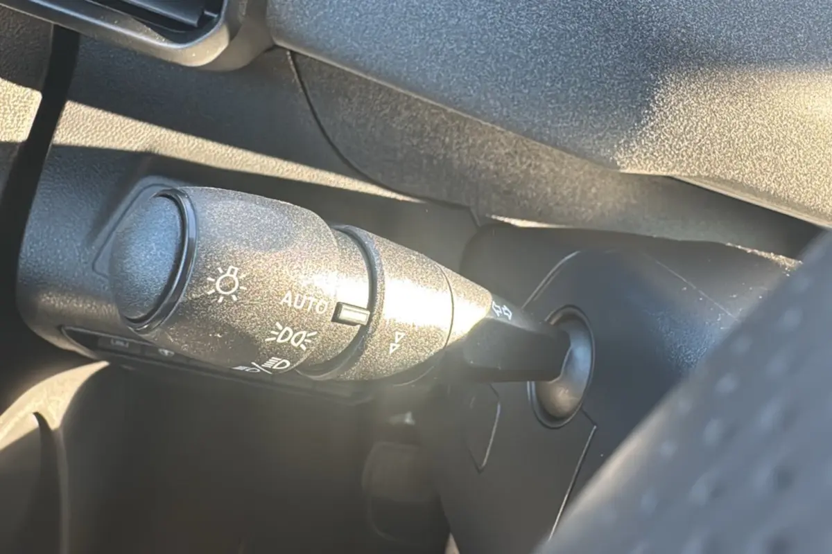 Gros plan sur la commande des feux et clignotants dans l’habitacle noir du Peugeot Rifter 2025.