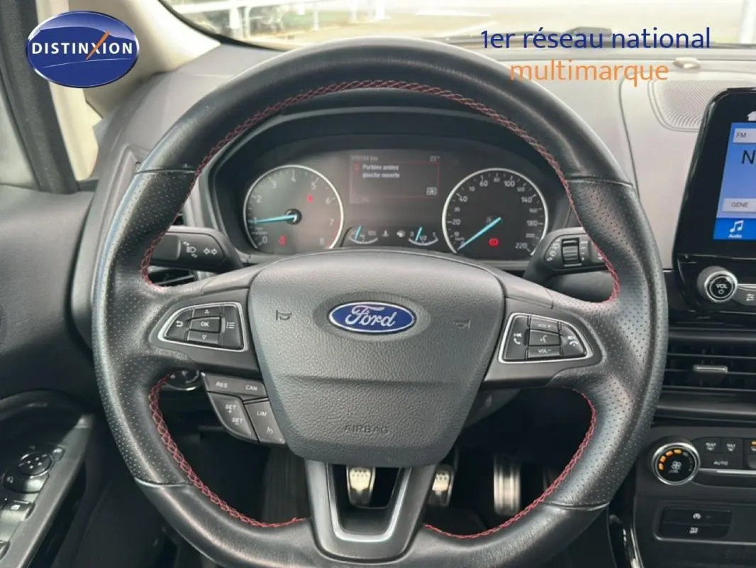 Vue rapprochée du volant en cuir noir avec surpiqûres rouges du Ford EcoSport gris clair, tableau de bord et écran tactile visibles.