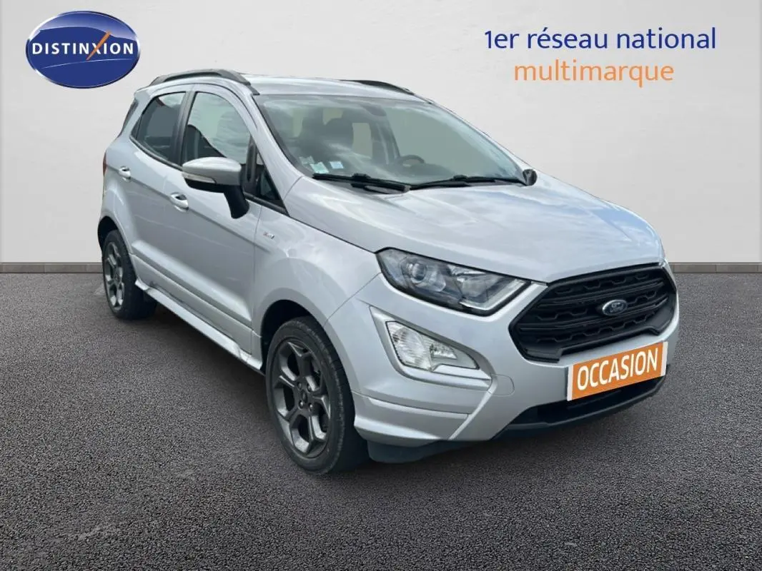 Ford EcoSport gris clair en 3/4 avant droit avec jantes alliage et barres de toit visibles sur fond neutre.