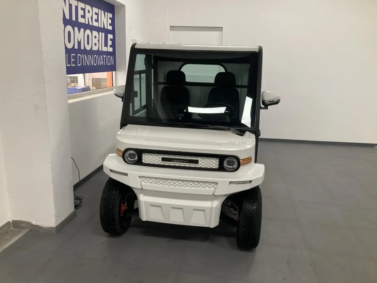 Vue frontale d'un véhicule électrique blanc Liberty L7E H2 160 avec kit ridelles et phares LED ronds.