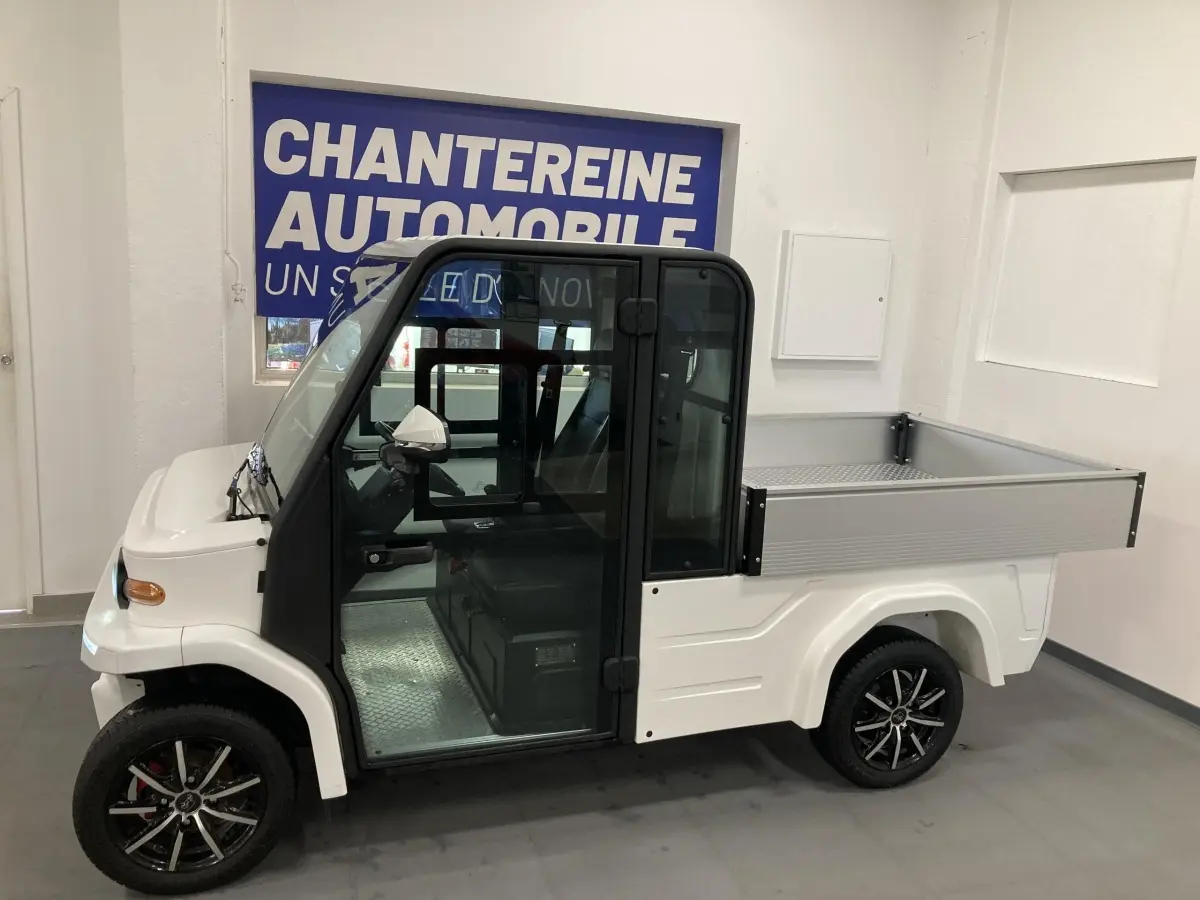 Vue de profil droit du véhicule utilitaire électrique LIBERTY L7E H2 160 blanc avec kit ridelles et jantes alliage 13 pouces.